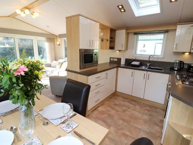 A kitchen and dining area with a table set for four and a living room with couches visible at Lodge 2 Silverdale