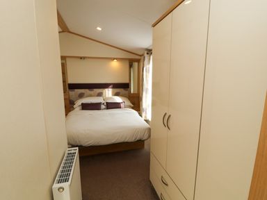 A bedroom with a double bed with pillows and a wardrobe at Lodge 2 in Silverdale