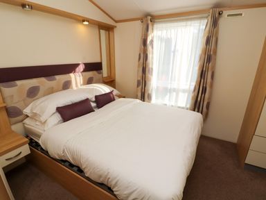 A bedroom with a double bed bedside tables and a window with curtains at Lodge 2 in Silverdale