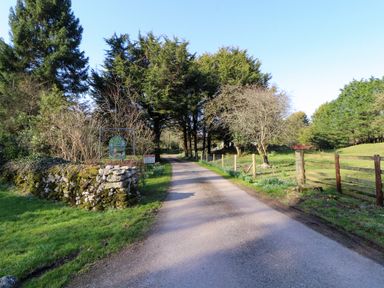 A country road with stone wall and signs surrounded by trees and grass at Lodge 2 in Silverdale
