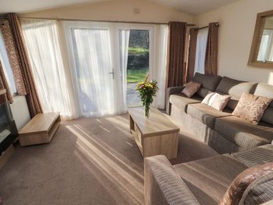 A living room with sofas and a coffee table with flowers near large glass doors at Lodge 3 in Silverdale