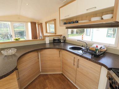 A kitchen corner with brown countertops wooden cabinets a sink with drying rack and dishes at Lodge 3 Silverdale
