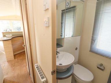 A small bathroom with a round sink, toilet, mirrored cabinet, and window blinds at Lodge 3 in Silverdale