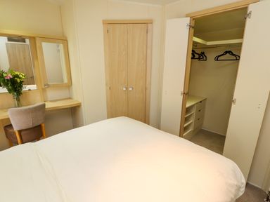 A bedroom with a bed a desk a chair an open closet with hangers and drawers at Lodge 3 Silverdale