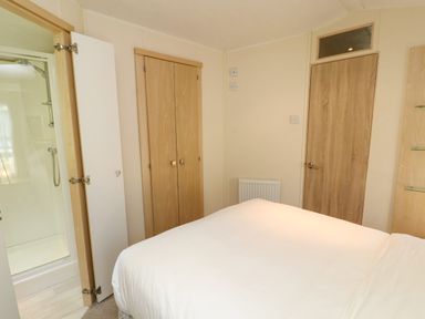 A bedroom with a bed a wardrobe two doors and a shower visible at Lodge 3 in Silverdale