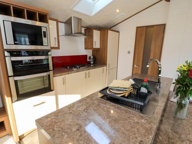 A kitchen with a stove oven microwave sink and countertop with dish drying rack at Lodge 4 in Silverdale