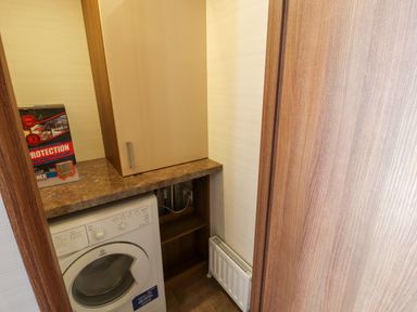 A small laundry area with a washing machine a countertop a cabinet a box and a radiator at Lodge 4 in Silverdale