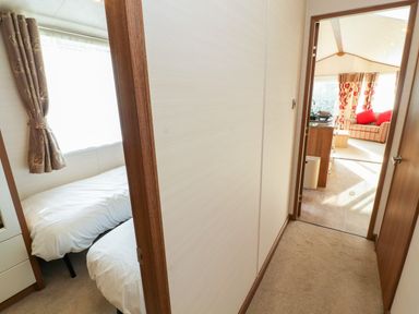 Hallway with doors leading to a bedroom with twin beds and a living room with a sofa at Lodge 4 in Silverdale