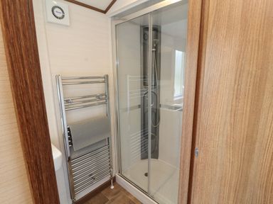 A bathroom with a shower enclosure and a towel rack with a towel at Lodge 4 in Silverdale