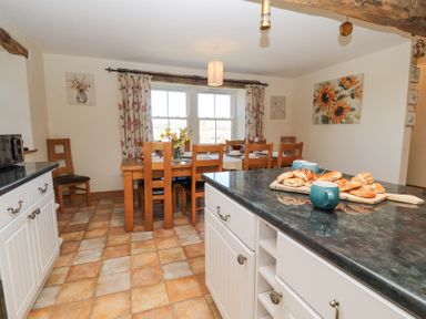 A kitchen dining area with a wooden dining table and chairs by a window at High Wood Foot in Bampton Cumbria