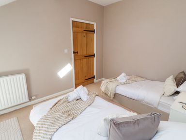 A bedroom with two single beds and a wooden door at High Wood Foot in Bampton Cumbria