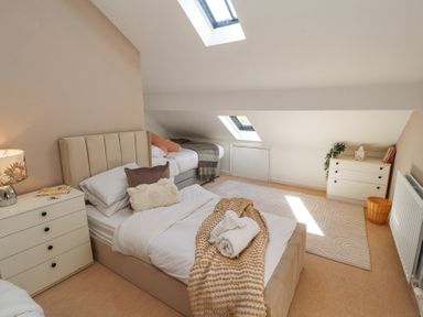 A bedroom with two single beds two white dressers a lamp books a radiator and skylight windows at High Wood Foot in Bampton Cumbria