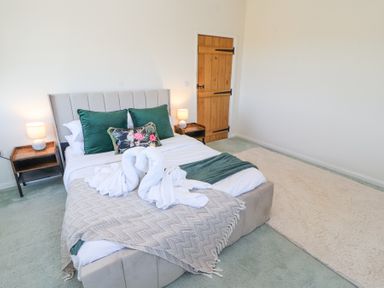 A bedroom with a bed with green pillows and a beige throw on a light green carpet at High Wood Foot in Bampton Cumbria