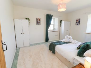 A bedroom with a double bed green curtains and two white wardrobes at High Wood Foot in Bampton Cumbria