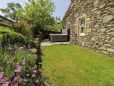 A garden with a hot tub and flowers at High Wood Foot in Bampton, Cumbria