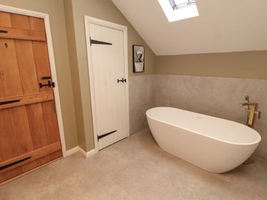 A bathroom with a bathtub and two doors at High Wood Foot in Bampton, Cumbria