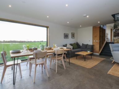 A dining room with a table and chairs at Tithe Barn Lodge Capel Mawr near Malltraeth