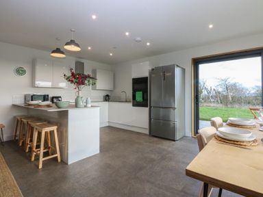 A kitchen with appliances and a table at Tithe Barn Lodge Capel Mawr near Malltraeth