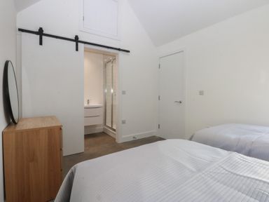 A bedroom with two beds and a wardrobe at Tithe Barn Lodge in Capel Mawr near Malltraeth