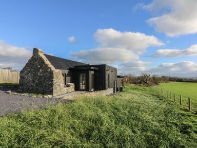 A building with a field and fence at Tithe Barn Lodge Capel Mawr near Malltraeth