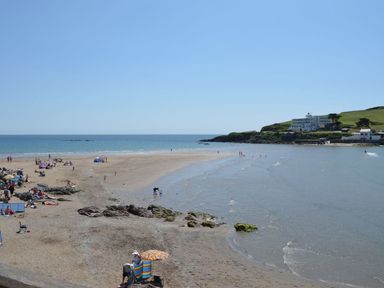 A beach with people on sand and near water with buildings and hills in the background at 6 Burgh Island in Bigbury-On-Sea