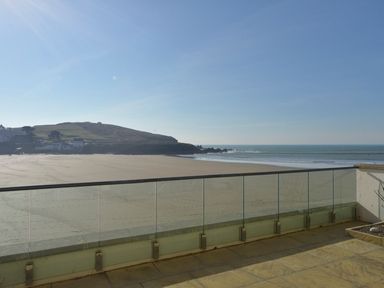 A beach view from a balcony with glass railing and a hill in the background at 6 Burgh Island in Bigbury-On-Sea