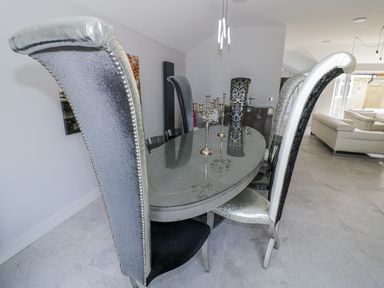 A dining room with a glass table and high back chairs at Chillon South Littleton near Honeybourne