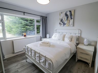 A bedroom with a bed, bedside table, and window at Chillon in South Littleton near Honeybourne