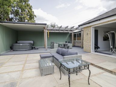 An outdoor living area with seating and a hot tub at Chillon South Littleton near Honeybourne