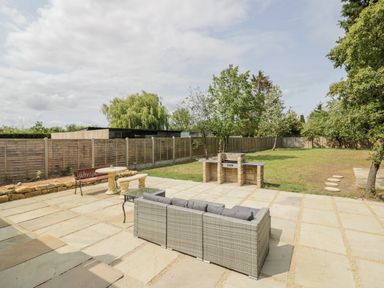 A garden with a patio, barbecue, and furniture at Chillon, South Littleton near Honeybourne