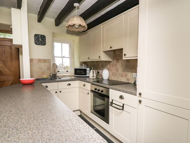 A kitchen with white cabinets a countertop a microwave kettle and an oven at Tyn Y Graig in Fairbourne
