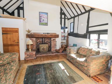A living room with two sofas a fireplace and a bookshelf at Wyre Court Cottage in Bewdley