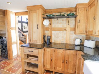 A kitchen with wooden cabinets black countertop white toaster and kettle at Wyre Court Cottage in Bewdley