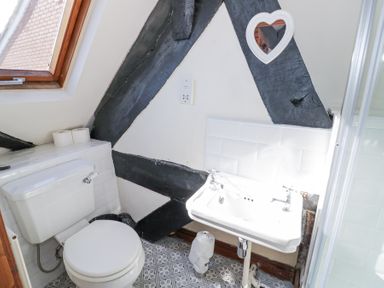 A bathroom with a toilet a sink a window and a heart shaped mirror at Wyre Court Cottage in Bewdley