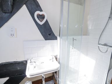 A bathroom with a white sink and a glass shower enclosure at Wyre Court Cottage in Bewdley