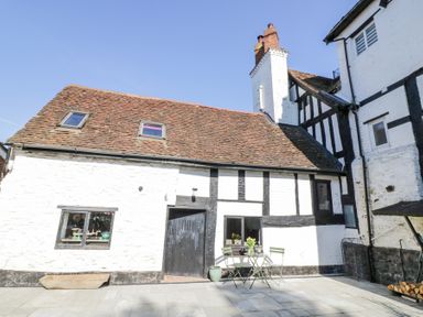 Exterior of a white and black timber framed cottage with a tiled roof and outdoor table with chairs at Wyre Court Cottage in Bewdley