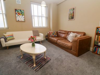 A living room with a brown leather sofa a white sofa a round coffee table with flowers and a bookshelf at Cottage Annex in Constantine