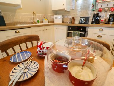 A kitchen with white cabinets and wooden countertop with a table set with plates cups and covered bowls with condiments at Cottage Annex in Constantine