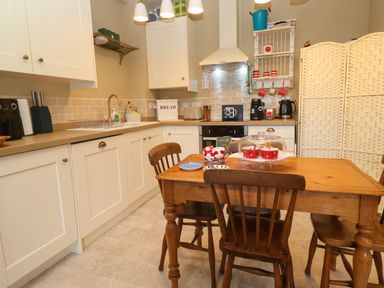 A kitchen with wooden table and chairs white cabinets and kitchen appliances at Cottage Annex in Constantine