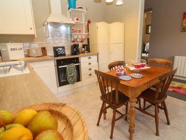 A kitchen with wooden table and chairs fruit bowl on counter and cooking appliances at Cottage Annex in Constantine
