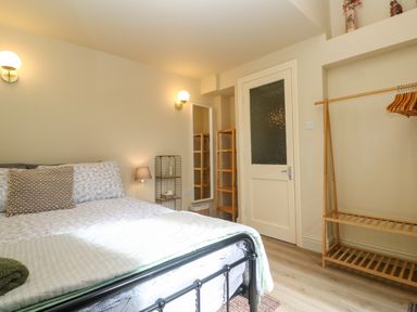 A bedroom with a bed a wall mirror wooden shelves and a clothing rack at Cottage Annex in Constantine