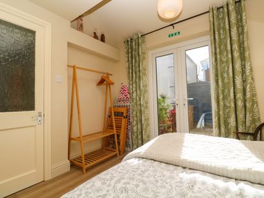 A bedroom with a bed near glass doors and green patterned curtains at Cottage Annex in Constantine
