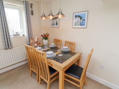 A dining room with a wooden table set for six with dishes and glasses at Sea Shore in Seahouses