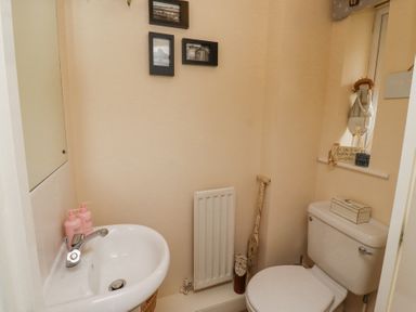 A small bathroom with a toilet and sink and wall pictures at Sea Shore in Seahouses