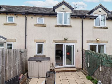 A backyard with patio tiles a storage shed sliding glass door and fenced sides at Sea Shore in Seahouses