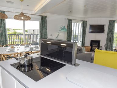 A kitchen with an induction hob and dining table at Dahlia in Portreath