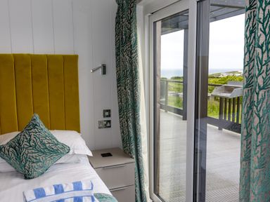 A bedroom with a bed and outdoor view at Dahlia in Portreath