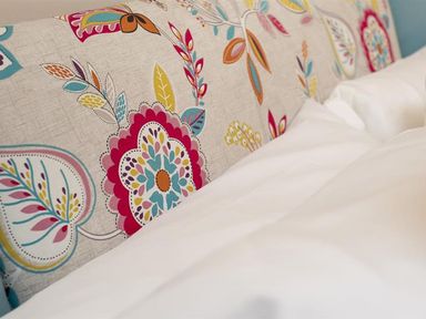 A bed with a floral patterned headboard and white bedding at Bellflower Cottage in Windermere