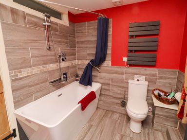 A bathroom with a bath tub and shower at Petty Knowes Cottage near Rochester