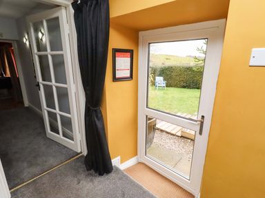 A hallway with a door leading to a garden at Petty Knowes Cottage Rochester near Otterburn